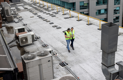 two people wearing a safety vest on a commercial roof
